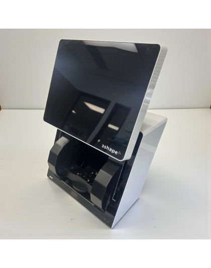 3Shape D710 desktop dental lab scanner on a white table, showing the front and side of the unit with its black scanning area and angled top panel.