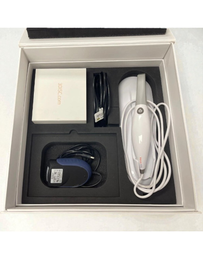 Open box of a 3DISC Heron IOS intraoral scanner showing the handpiece with cable, power adapter, connection cable and accessory box arranged in black foam packaging.